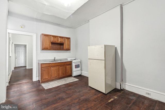 kitchen featuring white appliances, brown cabinetry, dark wood-type flooring, light countertops, and a sink