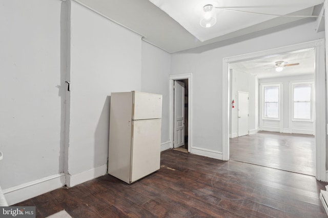 spare room featuring a baseboard radiator, baseboards, and dark wood-type flooring