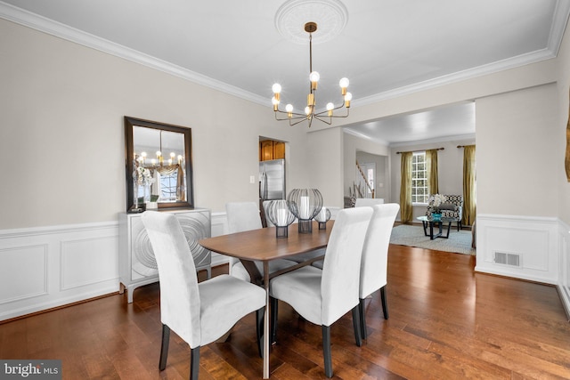 dining room featuring ornamental molding, dark wood finished floors, visible vents, and an inviting chandelier