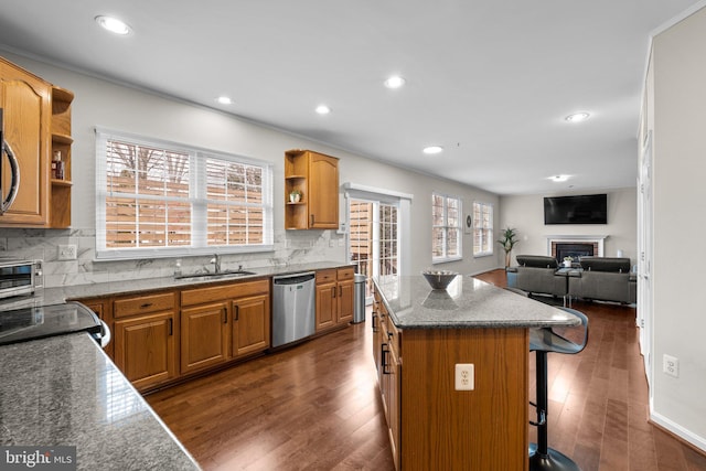 kitchen with a center island, stainless steel dishwasher, a fireplace, open shelves, and a sink