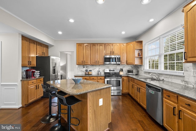 kitchen featuring stainless steel appliances, a kitchen island, a sink, and dark wood finished floors