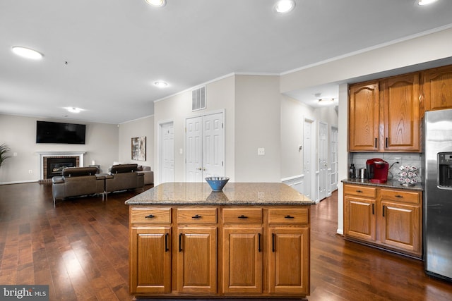 kitchen featuring stainless steel fridge, visible vents, decorative backsplash, dark stone countertops, and dark wood-type flooring