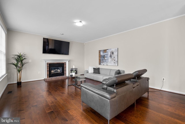 living room with ornamental molding, a brick fireplace, wood-type flooring, and baseboards