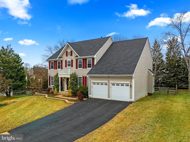 colonial house featuring aphalt driveway, a front lawn, fence, and an attached garage