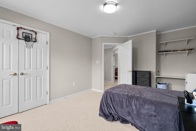 carpeted bedroom with a closet, baseboards, and crown molding