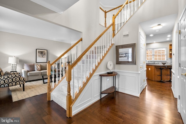 stairway with recessed lighting, a wainscoted wall, crown molding, and hardwood / wood-style flooring