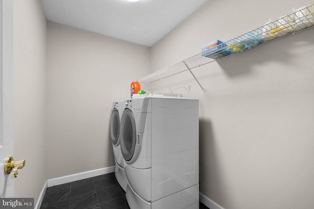 laundry area featuring laundry area, dark tile patterned flooring, washer and clothes dryer, and baseboards