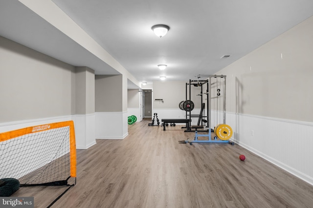 workout room with wainscoting, visible vents, and wood finished floors