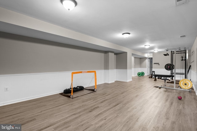 workout room with a wainscoted wall, wood finished floors, and visible vents