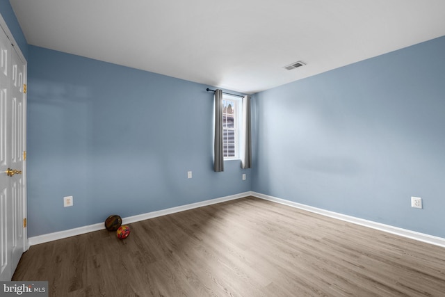 spare room with baseboards, visible vents, and wood finished floors