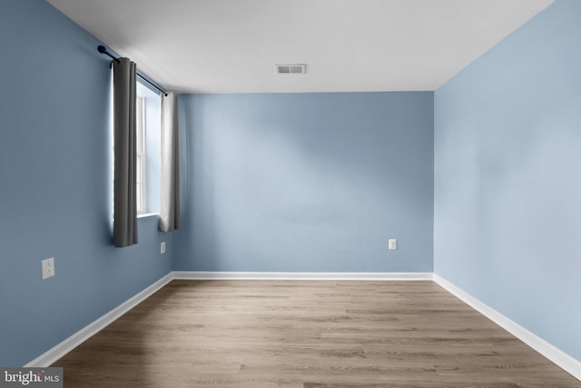 unfurnished room with visible vents, baseboards, and wood finished floors