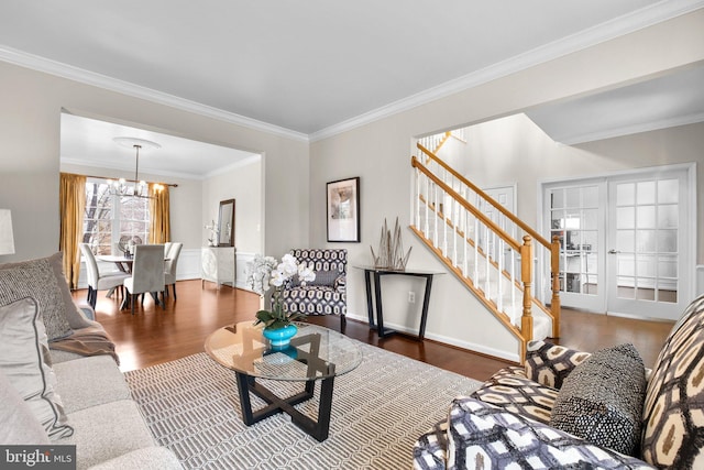 living room with ornamental molding, stairway, an inviting chandelier, and wood finished floors