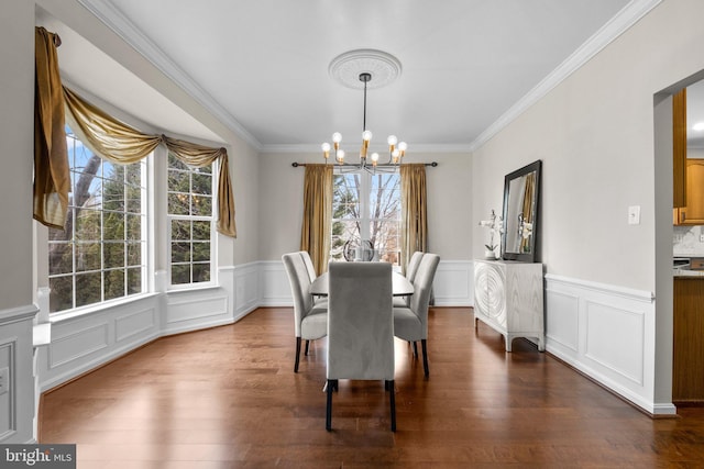 dining area with a chandelier, ornamental molding, and dark wood-style floors