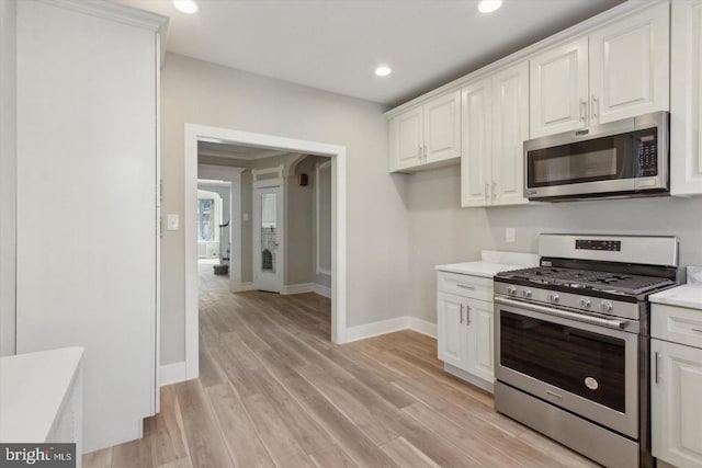 kitchen with stainless steel appliances, light countertops, light wood-style flooring, and white cabinets