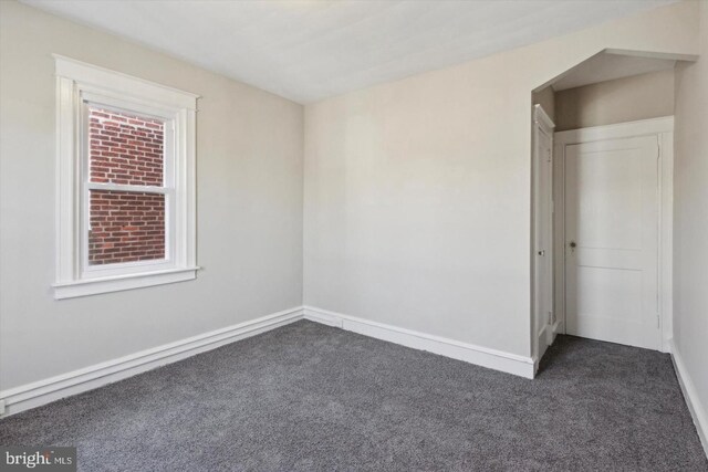 unfurnished bedroom featuring baseboards and dark carpet