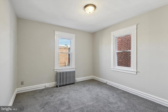 spare room with radiator heating unit, baseboards, and carpet flooring