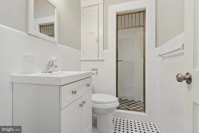 bathroom with toilet, a stall shower, tile walls, and vanity