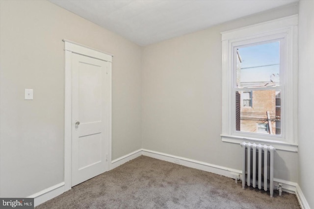 spare room with carpet, radiator heating unit, and baseboards