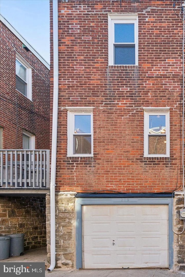 view of side of property featuring a garage, stone siding, and brick siding