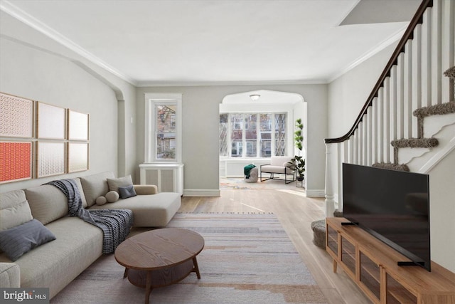 living room featuring arched walkways, wood finished floors, stairs, and crown molding