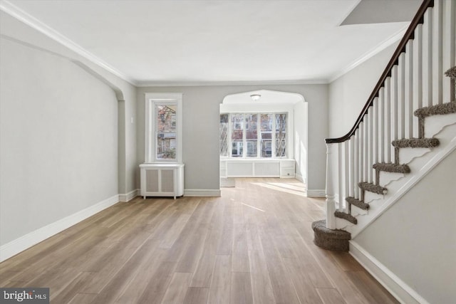 foyer entrance with baseboards, crown molding, radiator heating unit, and wood finished floors