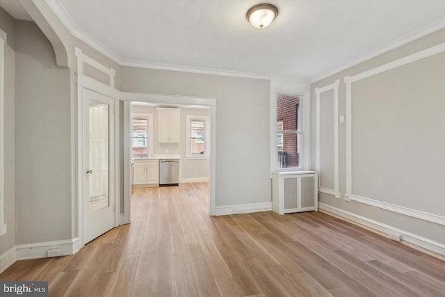 unfurnished room featuring ornamental molding, baseboards, light wood finished floors, and radiator heating unit