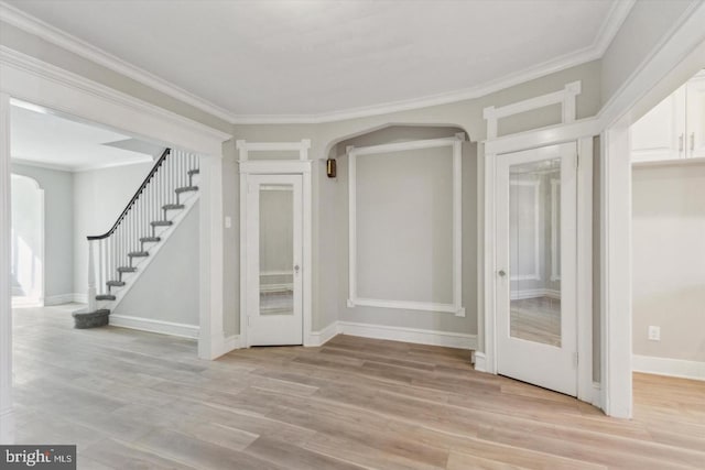 interior space with light wood-style floors, ornamental molding, baseboards, and stairs