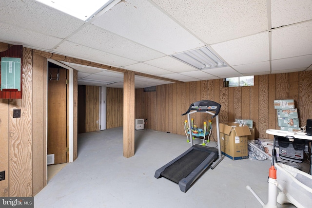 exercise area featuring a drop ceiling and wooden walls