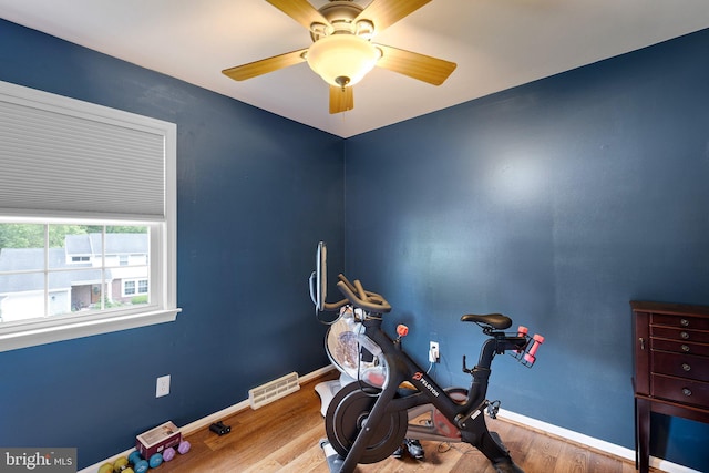 exercise area featuring visible vents, ceiling fan, baseboards, and wood finished floors