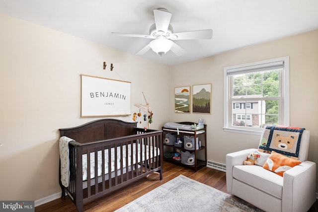 bedroom featuring visible vents, a ceiling fan, wood finished floors, a nursery area, and baseboards