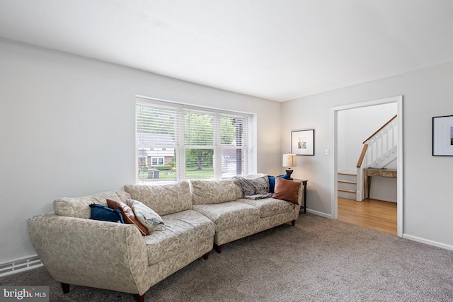 living area with carpet, stairway, and baseboards