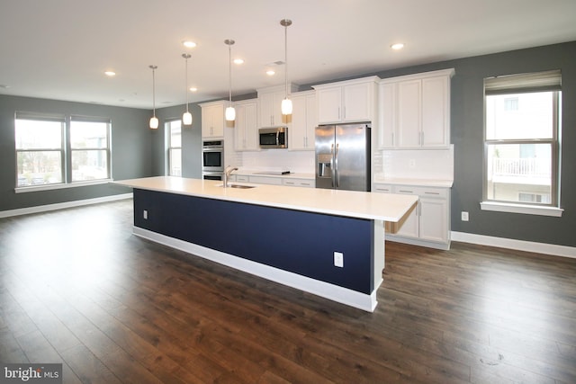 kitchen with an island with sink, a sink, light countertops, appliances with stainless steel finishes, and white cabinetry