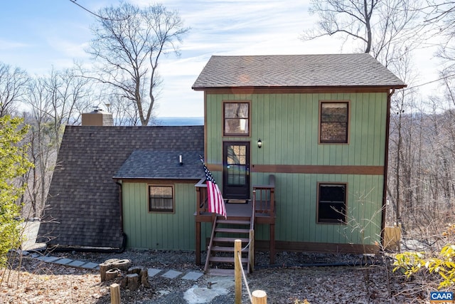 view of front facade with roof with shingles and a chimney