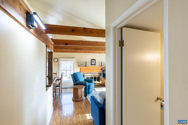 corridor featuring beamed ceiling, baseboards, and wood-type flooring