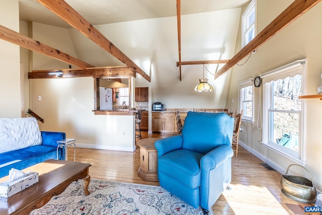 living area featuring visible vents, light wood-style flooring, baseboards, and a towering ceiling