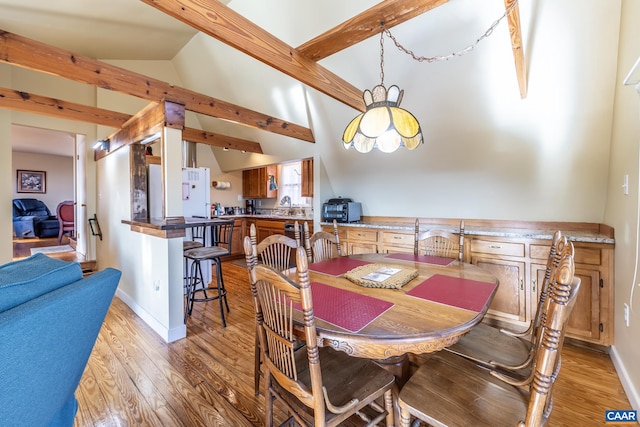 dining area with beamed ceiling, high vaulted ceiling, light wood-style flooring, a toaster, and baseboards