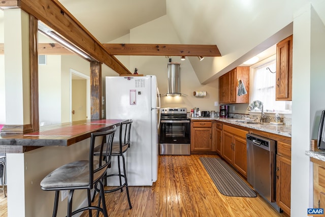 kitchen with ventilation hood, lofted ceiling, brown cabinets, appliances with stainless steel finishes, and light wood-style flooring