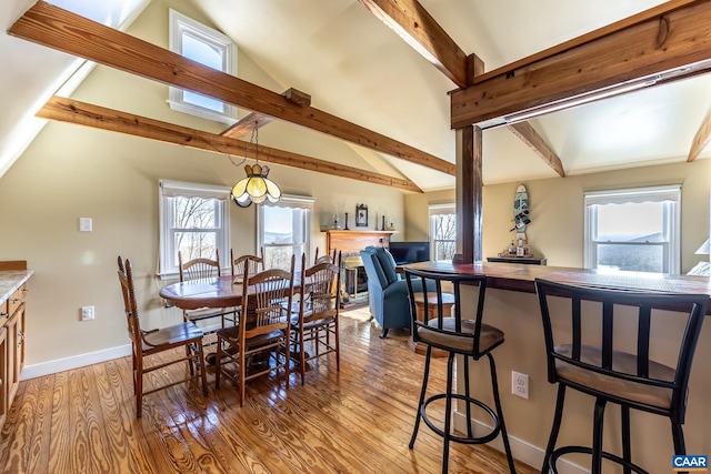 dining space featuring lofted ceiling with beams, light wood-style flooring, and plenty of natural light