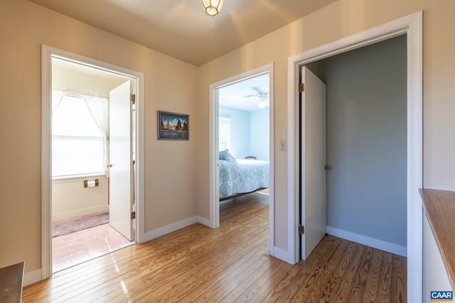 corridor with light wood-style floors and baseboards