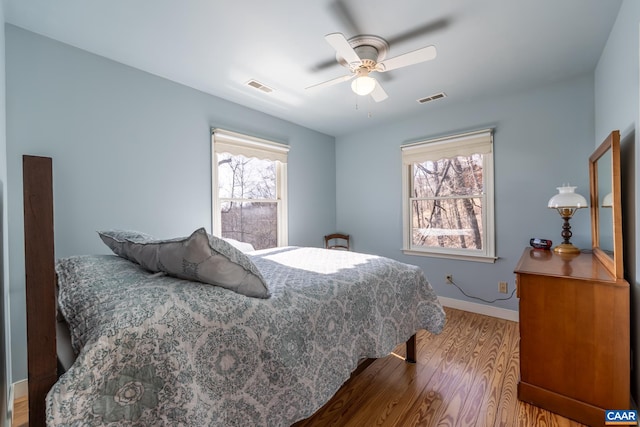 bedroom with visible vents, multiple windows, and wood finished floors