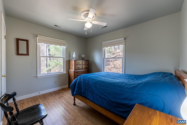 bedroom featuring ceiling fan, wood finished floors, visible vents, and baseboards