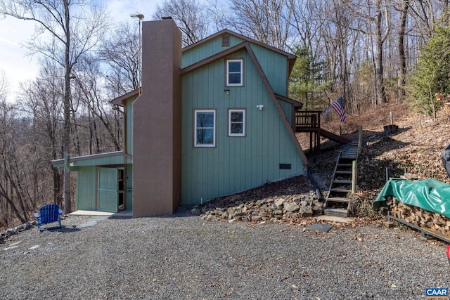 view of side of home with stairs and a chimney