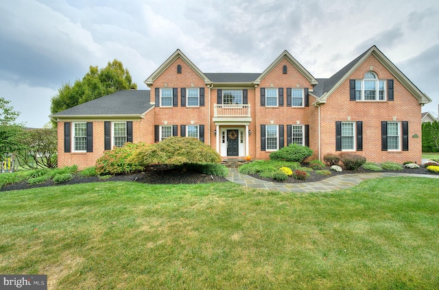 colonial home featuring brick siding and a front yard