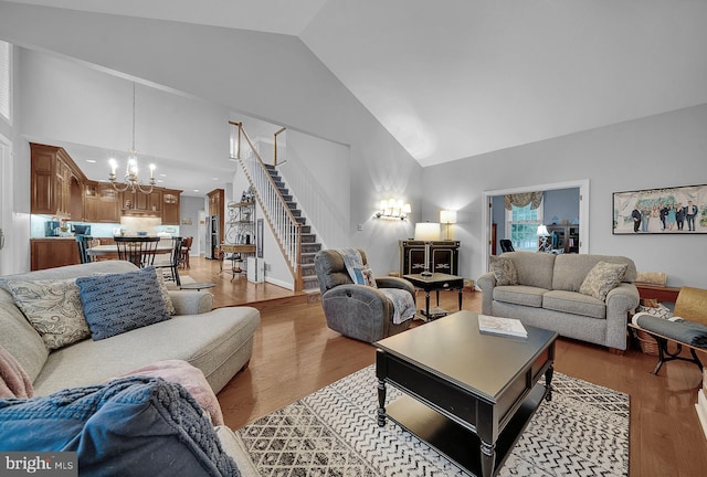 living area featuring light wood finished floors, stairway, a chandelier, and high vaulted ceiling