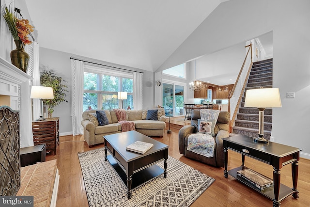 living area with a chandelier, wood finished floors, high vaulted ceiling, and stairs