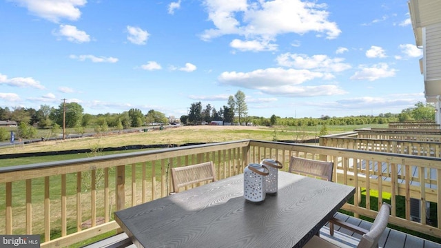 deck with a yard, a rural view, and outdoor dining space