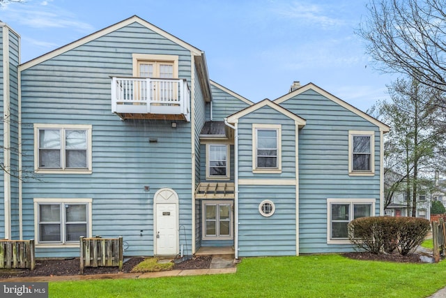 townhome / multi-family property featuring a balcony and a front lawn