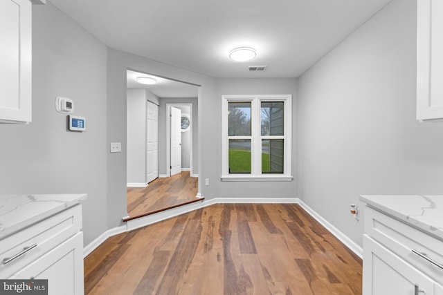 unfurnished dining area featuring visible vents, baseboards, and wood finished floors