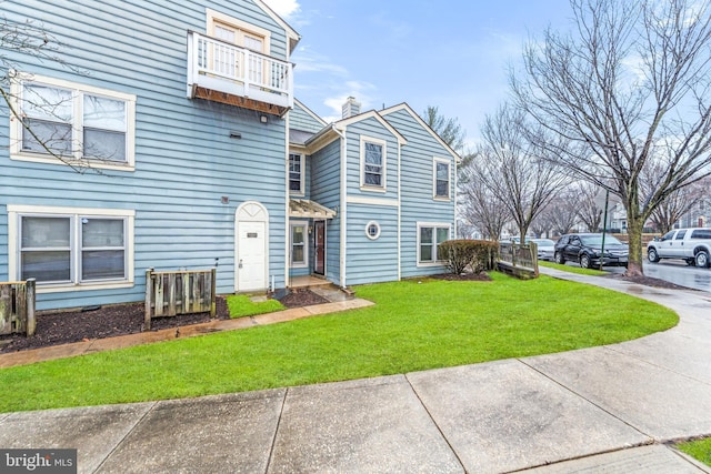 view of front of house with a balcony and a front yard