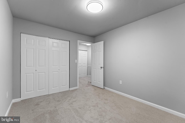 unfurnished bedroom with a closet, carpet, and baseboards